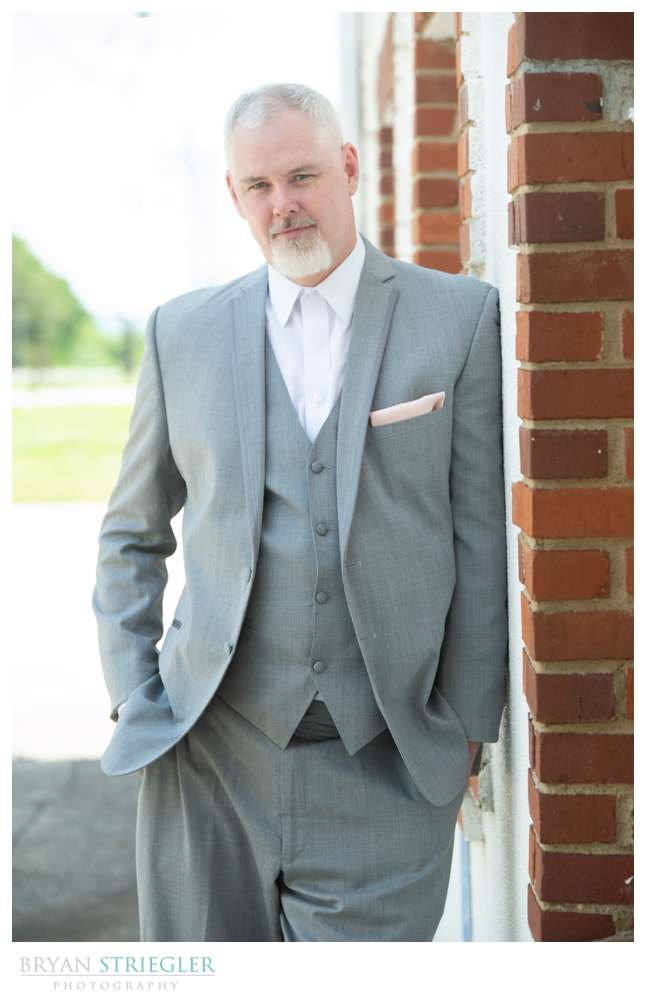 groom leaning against wall